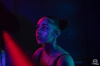 a woman with tattoos and a neon light in front of her