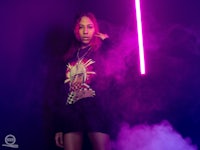 a girl with a purple light saber in front of smoke