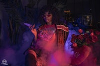 a woman sitting on a bed with smoke coming out of her hair