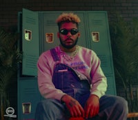 a man in overalls sitting in front of lockers