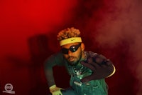 a man in overalls posing in front of a red background