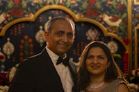 a man and woman posing for a photo in front of an ornate backdrop