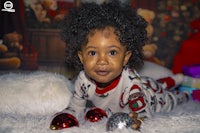 a little girl in a christmas pajama laying on the floor