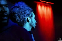 a man with afro hair standing in front of a red light