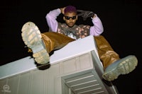 a man with purple hair sitting on top of a building