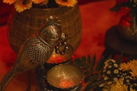 a bird sits on a table next to a vase of flowers