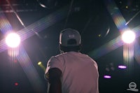 a man in a hat standing in front of bright lights