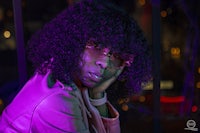 a woman with curly hair sitting in front of a window