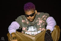 a man with purple hair sitting on the ground