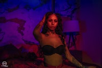 a woman in lingerie sitting on a bed in a dark room