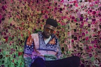 a man sitting in front of a wall covered in stickers