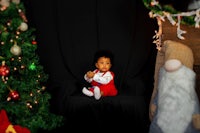a baby sitting in front of a christmas tree