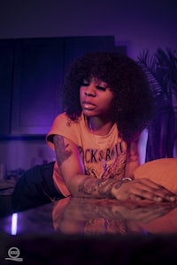 a woman with tattoos laying on a table in a kitchen