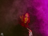 a woman with red hair standing in front of smoke