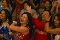 a group of indian women dancing at a wedding reception