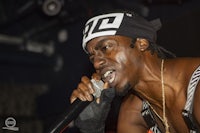 a black man holding a microphone and wearing a bandana